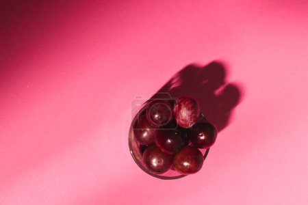 Foto de Primer plano del vaso de uvas rojas y copia el espacio sobre fondo rosa. Concepto de frutas, alimentos, frescura y color. - Imagen libre de derechos