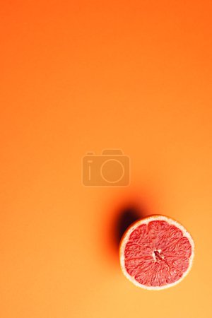 Photo for Close up of half of red grapefruit and copy space on orange background. Fruit, food, freshness and colour concept. - Royalty Free Image