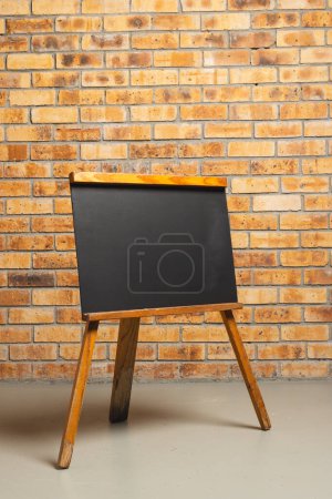 Photo for Black sign in wooden frame and copy space on brick wall background. Signage, writing space and advertising concept. - Royalty Free Image