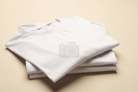Téléchargez les photos : Gros plan des t-shirts pliés blancs et de l'espace de copie sur fond jaune. Mode, vêtements, concept de couleur et de tissu. - en image libre de droit
