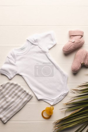 Photo for Flat lay of white baby grow, hat, dummy and pink booties with copy space on white background. Baby fashion, clothes, colour and fabric concept. - Royalty Free Image