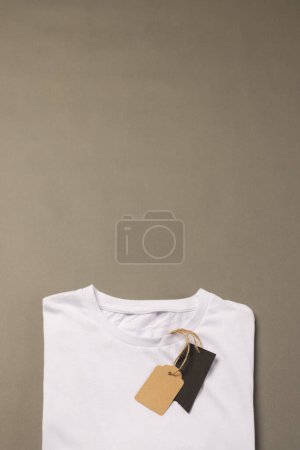 Foto de Camiseta blanca plegada con etiquetas con espacio de copia sobre fondo marrón. Moda, ropa, color y concepto de tela. - Imagen libre de derechos