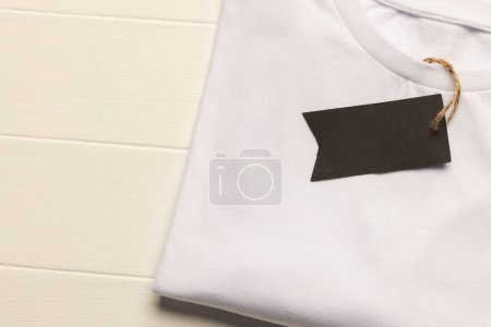 Photo for Close up of flat lay of white t shirt with tag and copy space on white boards background. Fashion, clothes, colour and fabric concept. - Royalty Free Image