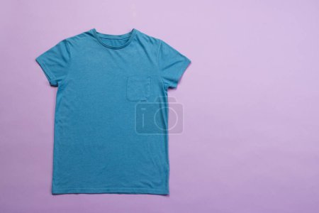 Téléchargez les photos : T-shirt bleu et espace de copie sur fond violet. Mode, vêtements, concept de couleur et de tissu. - en image libre de droit