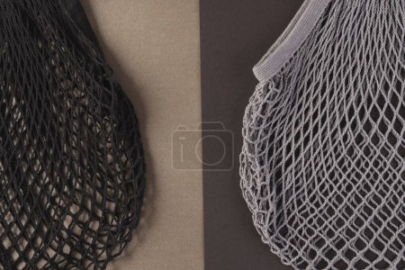 Photo for Black and grey mesh net bags with copy space on light and dark brown background. Shopping, bag, colour, fabric, texture and materials concept. - Royalty Free Image