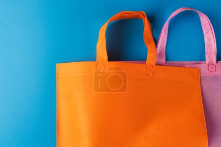Foto de Bolso de lona naranja y rosa con espacio para copiar sobre fondo azul. Compras, bolsa, color, tela, textura y concepto de materiales. - Imagen libre de derechos