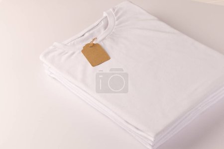 Photo for Stack of white t shirts with tag and copy space on white background. Fashion, clothes, colour and fabric concept. - Royalty Free Image