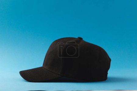 Foto de Gorra de béisbol negra y espacio de copia sobre fondo azul. Moda, ropa, color y concepto de tela. - Imagen libre de derechos
