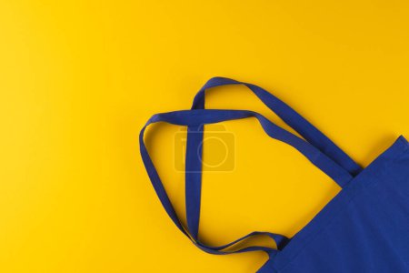 Téléchargez les photos : Gros plan du sac en toile bleue avec espace de copie sur fond jaune. Shopping, sac, couleur, tissu, texture et matériaux concept. - en image libre de droit