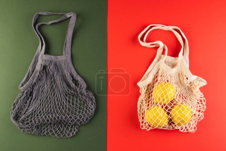 Photo for Brown and white mesh net bags with lemons and copy space on red and dark green background. Shopping, bag, colour, fabric, texture and materials concept. - Royalty Free Image