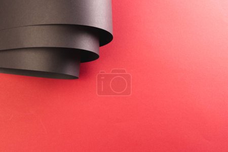 Téléchargez les photos : Gros plan de morceaux enroulés de papier noir avec espace de copie sur fond rouge. Concept papier, écriture, texture et matériaux. - en image libre de droit