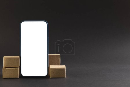 Photo for Smartphone with blank screen and cardboard boxes with copy space on black background. Cyber monday, cyber shopping, retail, technology, electronic device and communication concept. - Royalty Free Image