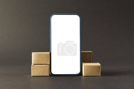 Photo for Smartphone with blank screen and cardboard boxes with copy space on black background. Cyber monday, cyber shopping, retail, technology, electronic device and communication concept. - Royalty Free Image