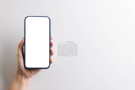 Photo for Hand of caucasian woman holding smartphone with blank screen and copy space on white background. Cyber technology, electronic device and communication concept. - Royalty Free Image