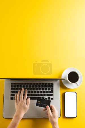 Photo for Vertical image of caucasian woman with credit card and laptop copy space on yellow background. Cyber shopping, retail, technology, electronic device and communication concept. - Royalty Free Image
