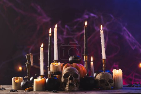Photo for Pumpkins, skulls and burning candles on purple background. Fall, autumn, halloween, tradition and celebration concept. - Royalty Free Image