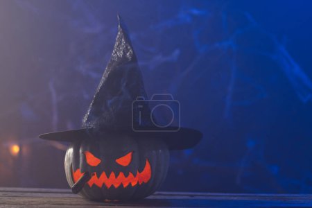 Téléchargez les photos : Citrouille sculptée portant un chapeau de sorcière avec un espace de copie sur fond bleu. Automne, automne, Halloween, concept de tradition et de célébration. - en image libre de droit