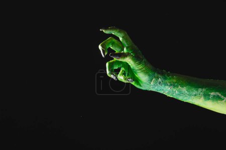 Téléchargez les photos : Main monstre vert avec des ongles noirs atteignant sur fond gris. Halloween, concept de tradition et célébration. - en image libre de droit