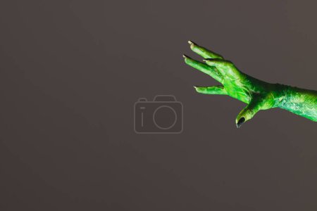 Foto de Mano monstruo verde con uñas negras que alcanzan sobre fondo gris. Halloween, tradición y concepto de celebración. - Imagen libre de derechos