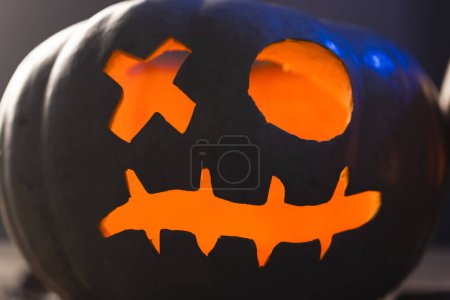 Foto de Cara de calabaza tallada iluminando con luz naranja sobre fondo negro. Otoño, otoño, halloween, tradición y concepto de celebración. - Imagen libre de derechos