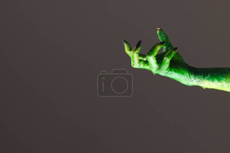 Photo for Green monster hand with black nails reaching on grey background. Halloween, tradition and celebration concept. - Royalty Free Image