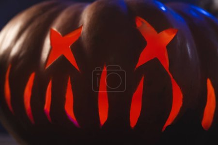Foto de Cara de calabaza tallada iluminando con luz roja sobre fondo negro. Otoño, otoño, halloween, tradición y concepto de celebración. - Imagen libre de derechos