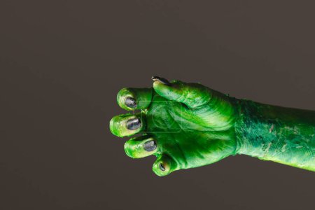 Téléchargez les photos : Main monstre vert avec des ongles noirs atteignant sur fond gris. Halloween, concept de tradition et célébration. - en image libre de droit