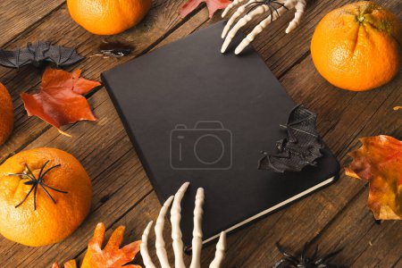 Foto de Decoraciones de Halloween y esqueleto manos en el cuaderno con espacio de copia sobre fondo marrón. Otoño, otoño, halloween, tradición y concepto de celebración. - Imagen libre de derechos