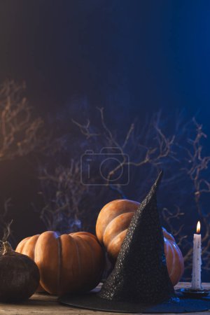 Foto de Imagen vertical de calabazas y sombrero de bruja y vela encendida con espacio de copia sobre fondo azul. Otoño, otoño, halloween, tradición y concepto de celebración. - Imagen libre de derechos