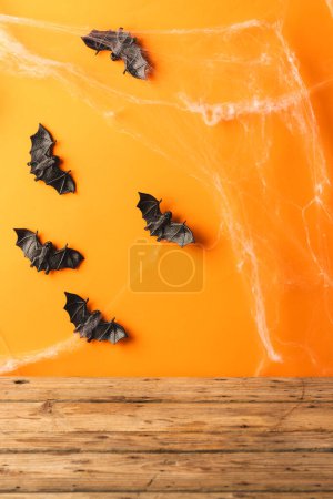 Foto de Imagen vertical de murciélagos de halloween y telarañas con espacio de copia sobre fondo naranja y marrón. Otoño, otoño, halloween, tradición y concepto de celebración. - Imagen libre de derechos
