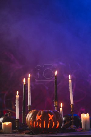 Photo for Vertical image of pumpkins and candles with copy space on purple background. Fall, autumn, halloween, tradition and celebration concept. - Royalty Free Image