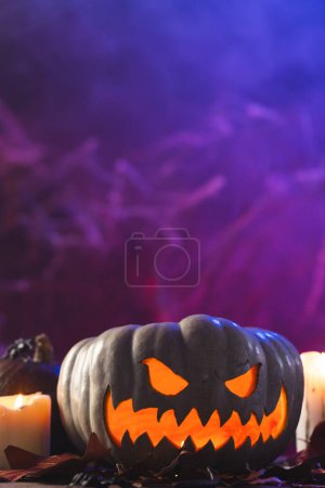 Photo for Vertical image of pumpkin and candles with copy space on purple background. Fall, autumn, halloween, tradition and celebration concept. - Royalty Free Image
