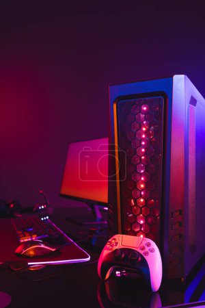 Photo for Vertical image of computer with video game accessories with copy space on neon background. Video game and digital connections concept digitally generated image. - Royalty Free Image