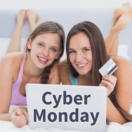 Photo for Cyber monday text over happy caucasian female friends lying on bed using laptop and credit card. Cyber monday, online shopping and sale promotion concept digitally generated image. - Royalty Free Image