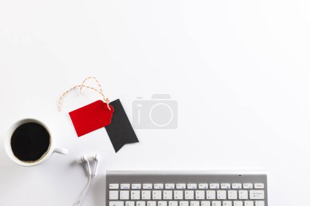Photo for Computer keyboard, earphones and gift tags with copy space on white background. Black friday, cyber monday, shopping, cyber shopping, sales, retail and shipping concept. - Royalty Free Image