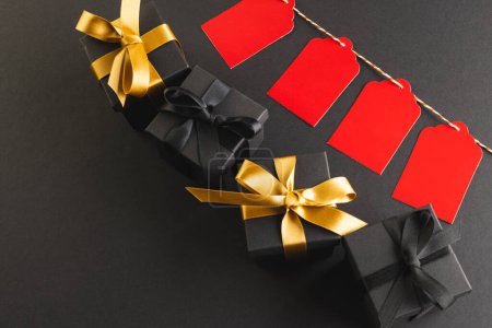 Photo for Red gift tags on pegs and black gift boxes with copy space over black background. Cyber monday, black friday, online shopping, shipping and global connections concept. - Royalty Free Image