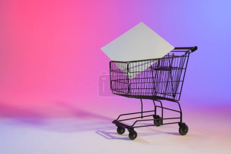 Photo for Shopping trolley with blank canvas and copy space over neon purple background. Cyber monday, black friday, online shopping, shipping and global connections concept. - Royalty Free Image