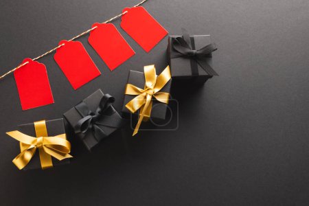 Photo for Red gift tags on pegs and black gift boxes with copy space over black background. Cyber monday, black friday, online shopping, shipping and global connections concept. - Royalty Free Image
