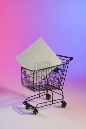 Photo for Vertical image of shopping trolley with blank canvas and copy space over neon purple background. Cyber monday, black friday, online shopping, shipping and global connections concept. - Royalty Free Image