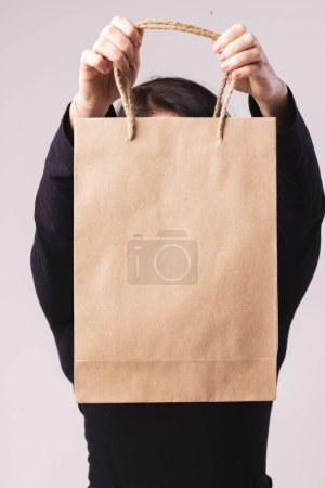 Photo for Caucasian woman holding paper shopping bag with copy space on white background. Black friday, cyber monday, shopping, cyber shopping, sales, retail and shipping concept. - Royalty Free Image