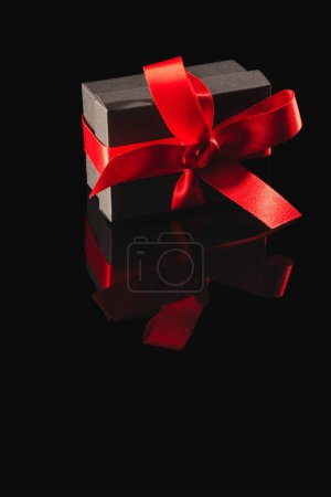 Foto de Caja de regalo negra con cinta y espacio para copiar sobre fondo negro. Cyber lunes, viernes negro, compras en línea, envío y concepto de conexiones globales. - Imagen libre de derechos