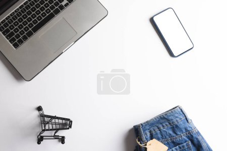 Photo for Laptop, shopping trolley and smartphone with copy space on white background. Cyber shopping, retail, technology, electronic device and communication concept. - Royalty Free Image