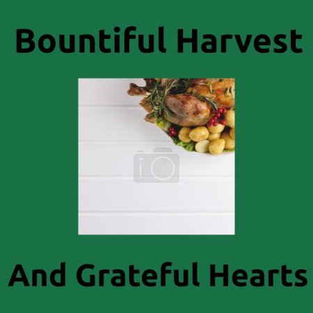 Photo for Bountiful harvest and grateful hearts text on green with thanksgiving dinner on table. Thanksgiving, harvest festival, american tradition, family and autumn celebration digitally generated image. - Royalty Free Image