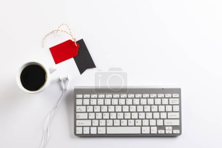 Photo for Computer keyboard, earphones and gift tags with copy space on white background. Black friday, cyber monday, shopping, cyber shopping, sales, retail and shipping concept. - Royalty Free Image
