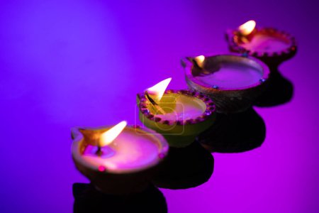 Téléchargez les photos : Gros plan de quatre bougies diwali avec espace de copie sur fond violet. Diwali, fête des lumières, religion, tradition hindoue et célébration. - en image libre de droit