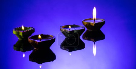 Foto de Cierre de cuatro velas diwali con espacio de copia sobre fondo púrpura. Diwali, festival de luces, religión, tradición hindú y celebración. - Imagen libre de derechos