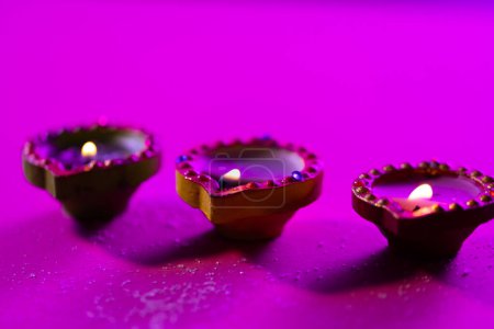 Photo for Close up of three diwali candles with copy space on purple background. Diwali, festival of lights, religion, hindu tradition and celebration. - Royalty Free Image