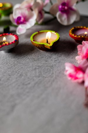 Téléchargez les photos : Gros plan des bougies diwali et des fleurs avec espace de copie sur fond gris. Diwali, fête des lumières, religion, tradition hindoue et célébration. - en image libre de droit