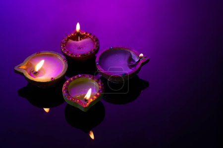 Téléchargez les photos : Gros plan de quatre bougies diwali avec espace de copie sur fond violet. Diwali, fête des lumières, religion, tradition hindoue et célébration. - en image libre de droit