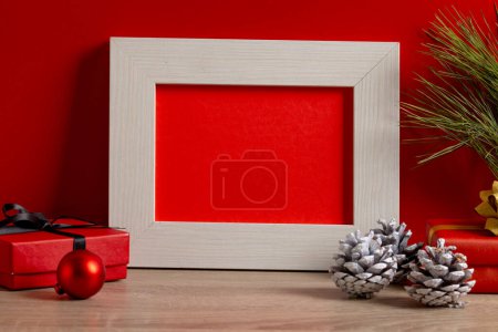 Foto de Decoraciones navideñas y marco de madera con espacio para copiar sobre fondo rojo. Navidad, decoraciones, tradición y concepto de celebración. - Imagen libre de derechos